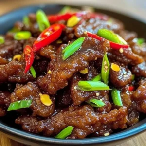 Plate of perfectly cooked Crispy Chilli Beef garnished with fresh herbs.