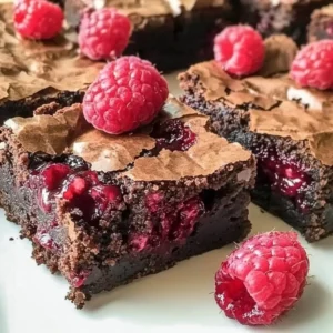 Delicious raspberry brownies topped with fresh berries and chocolate drizzle.