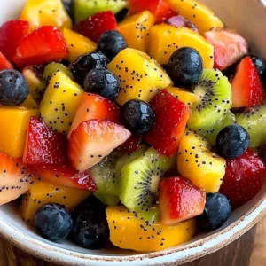 Fresh fruit salad topped with honey lime poppy seed dressing in a bowl.