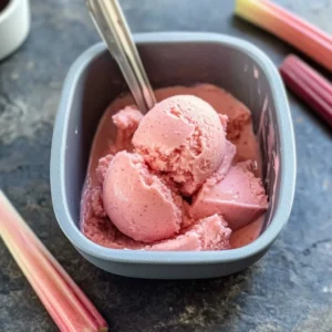 A vibrant bowl of homemade rhubarb sorbet garnished with fresh mint leaves.