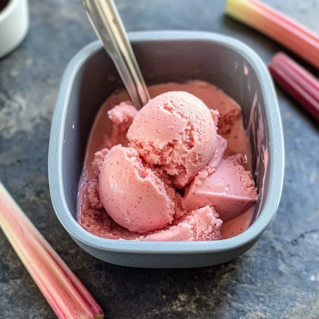 A vibrant bowl of homemade rhubarb sorbet garnished with fresh mint leaves.