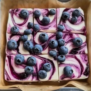 Blueberry cheesecake yogurt bark topped with fresh blueberries and drizzled with yogurt.